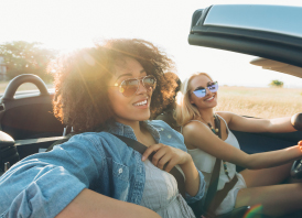 Women in a convertible driving at sunset
