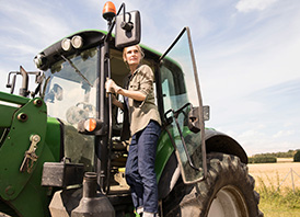 Woman stepping out of tractor on a farm