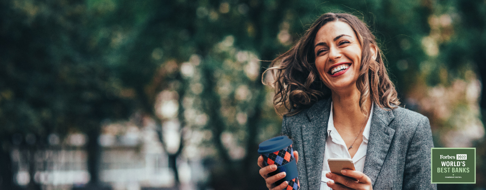 Smiling woman with a cup and phone