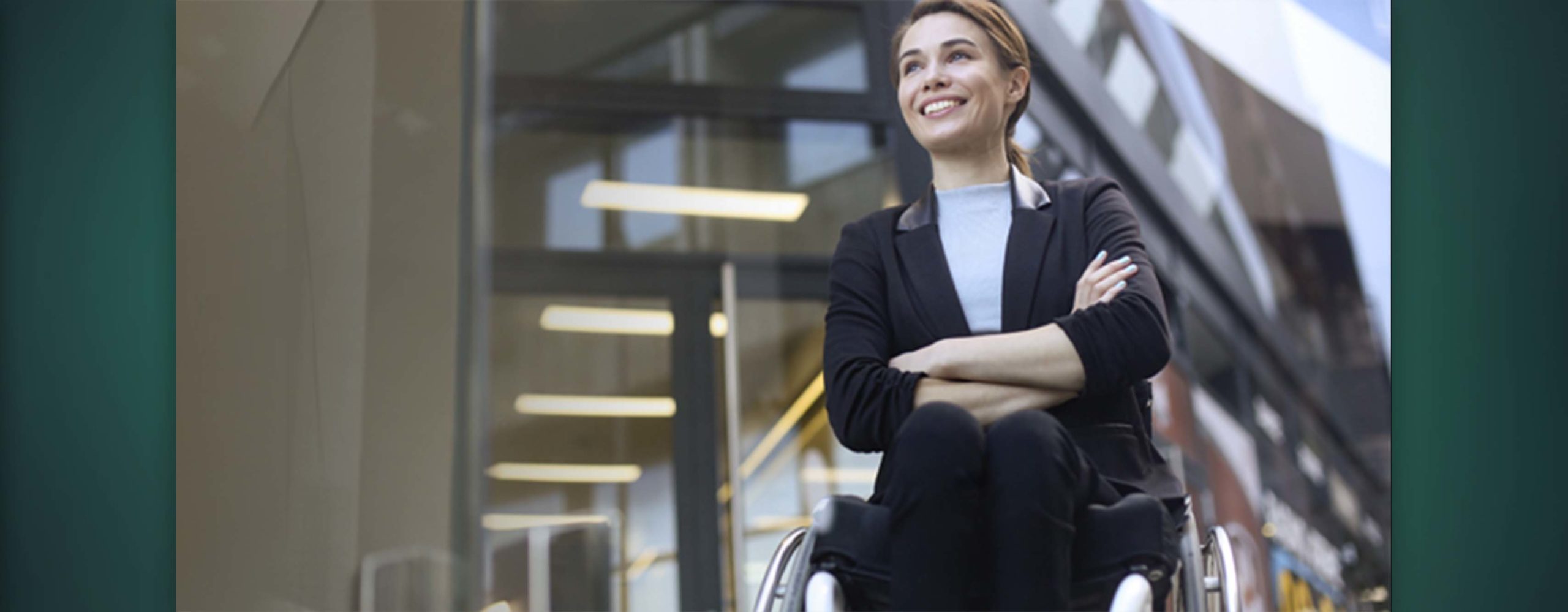 A smiling woman in a wheelchair inside an office building