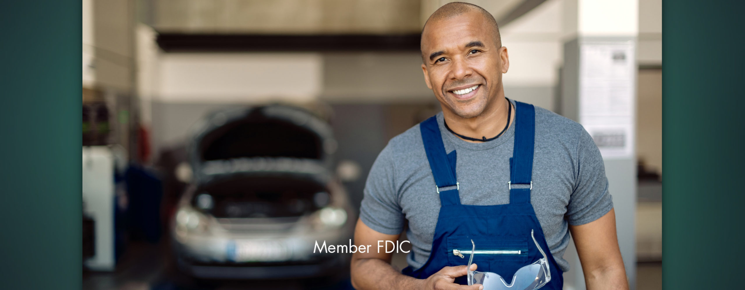 An auto repair shop owner smiling in front of his workshop