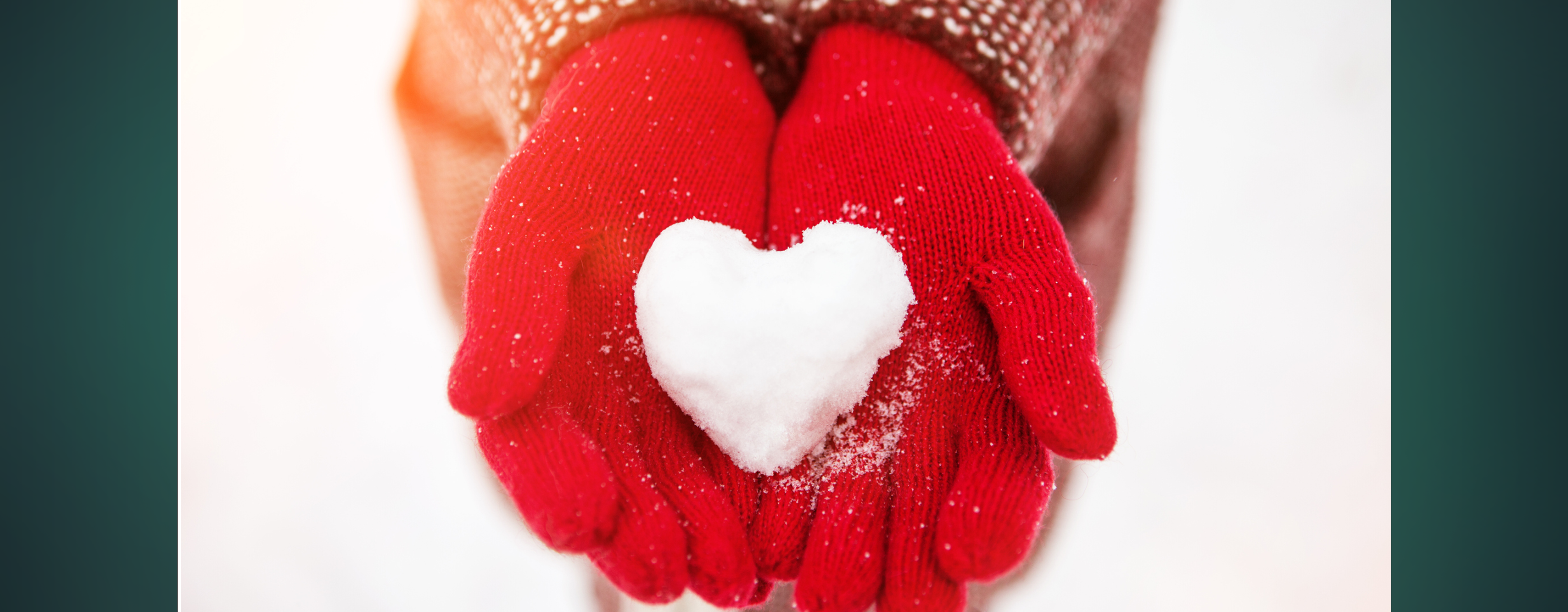 Close up of gloved hands holding a snowball in the shape of a heart