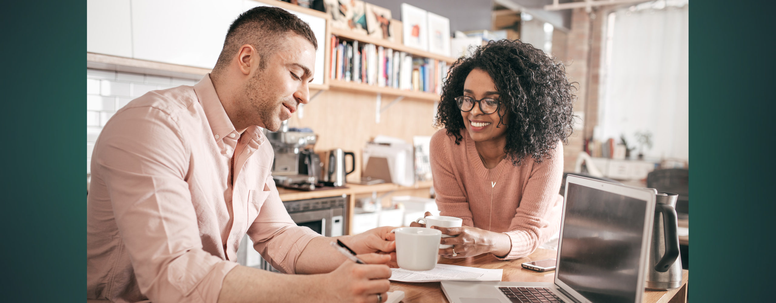 A couple looking over their budget together as they have a cup of coffee at their dining table