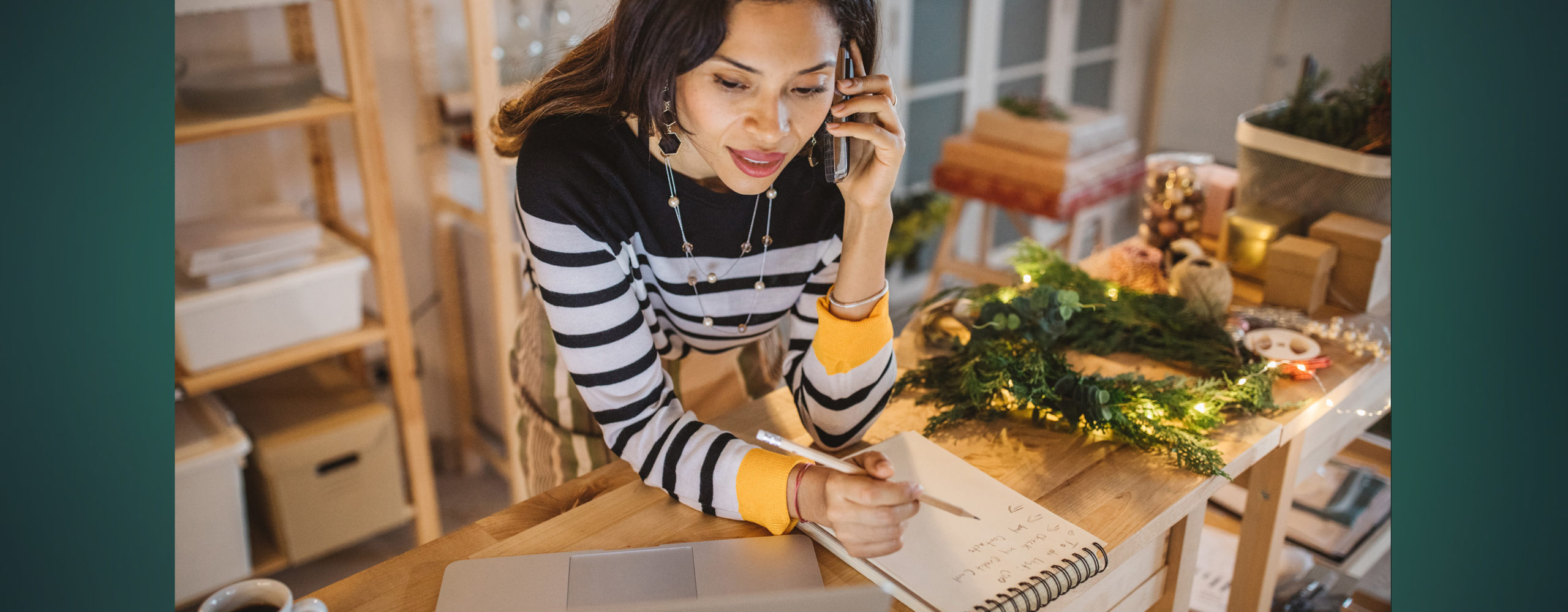 A woman talking on the phone and writing notes on a notepad