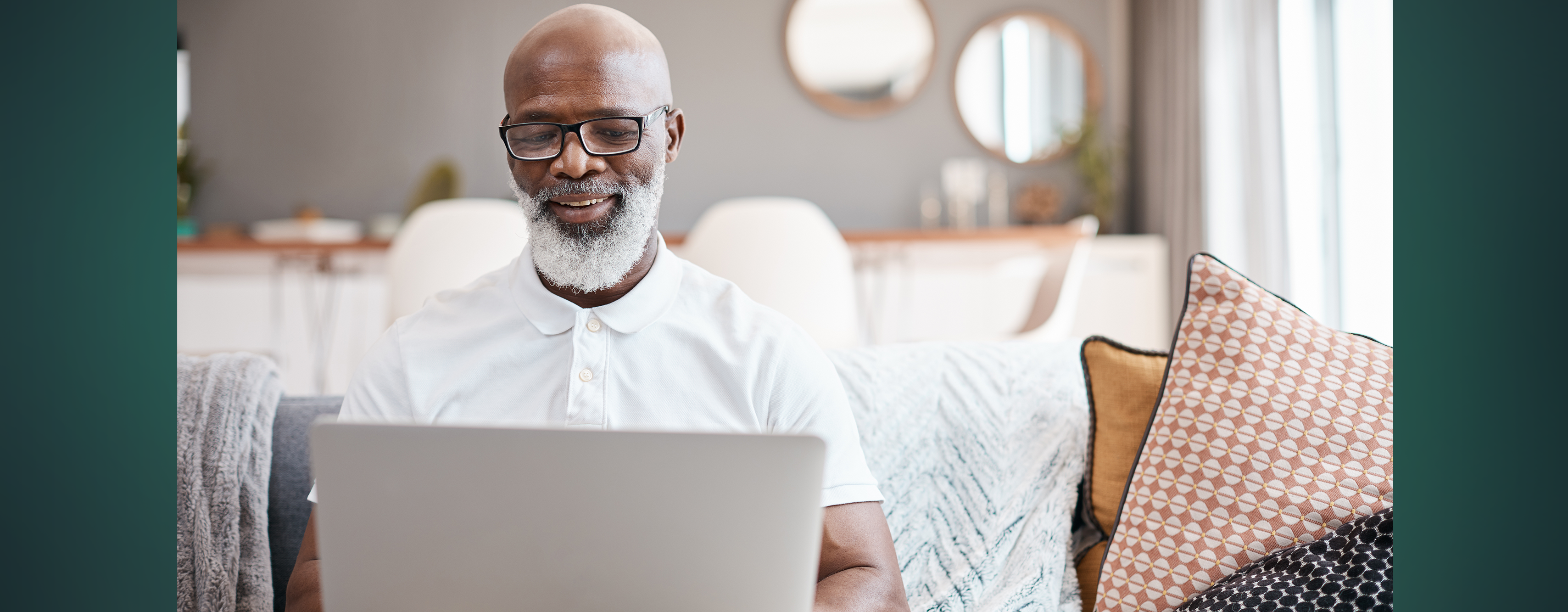 A man smiling as he looks at his laptop