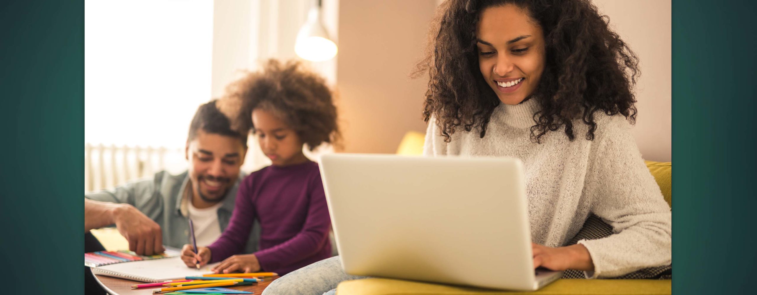 A woman looking at her laptop while her husband and daughter are working on homework behind her