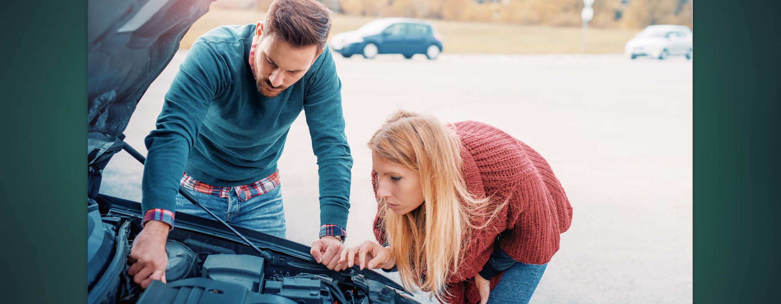 A couple looking under the hood of their car