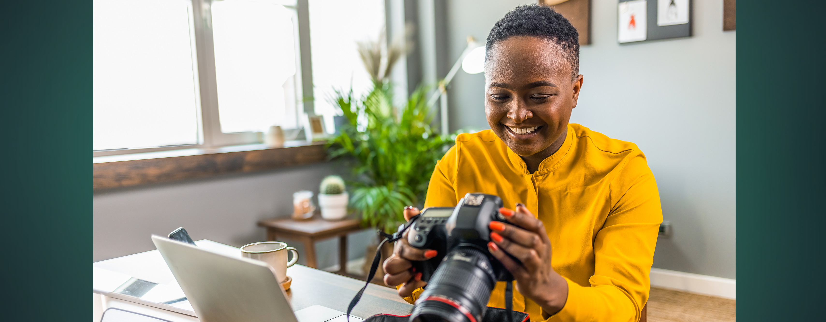 A smiling photographer looking at photos on her camera while sitting down at a desk
