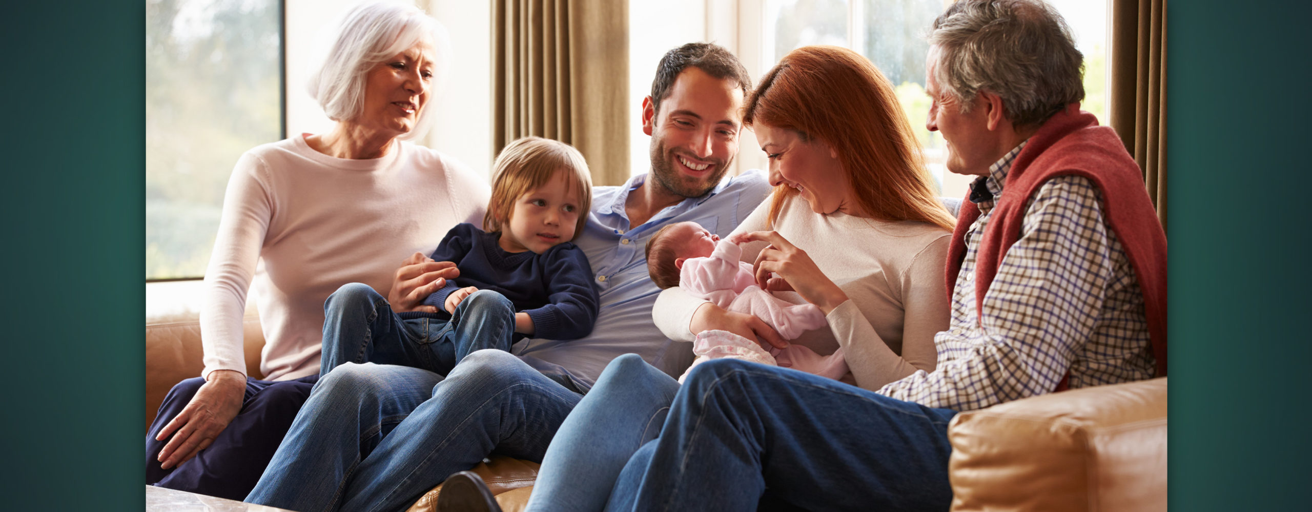 A multigenerational family of six, including grandparents, parents, a young child, and a newborn, sitting together and smiling.