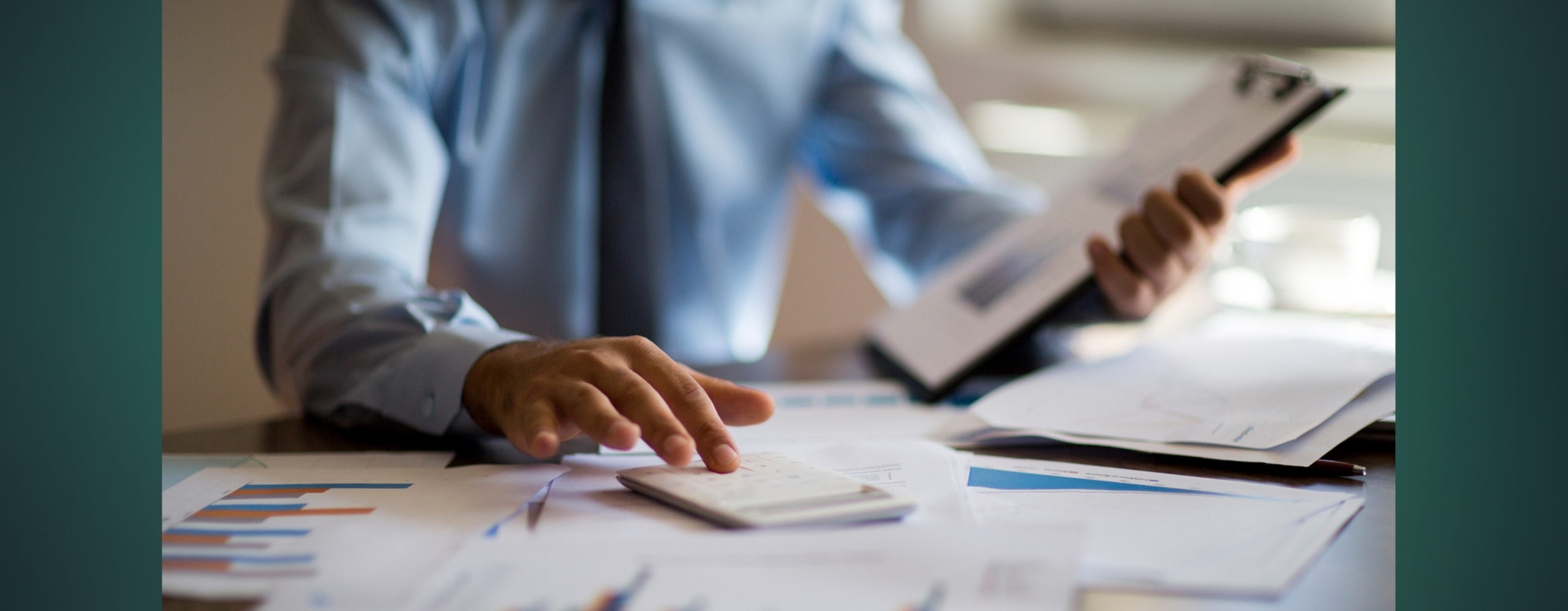 A man balancing his budget using a calculator and his financial documents