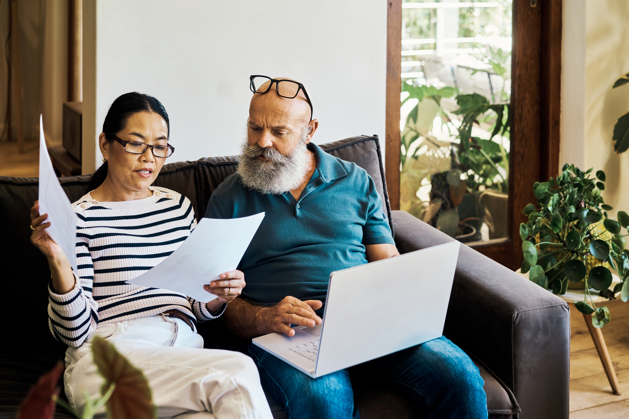 A middle aged couple reviewing papers together on their couch