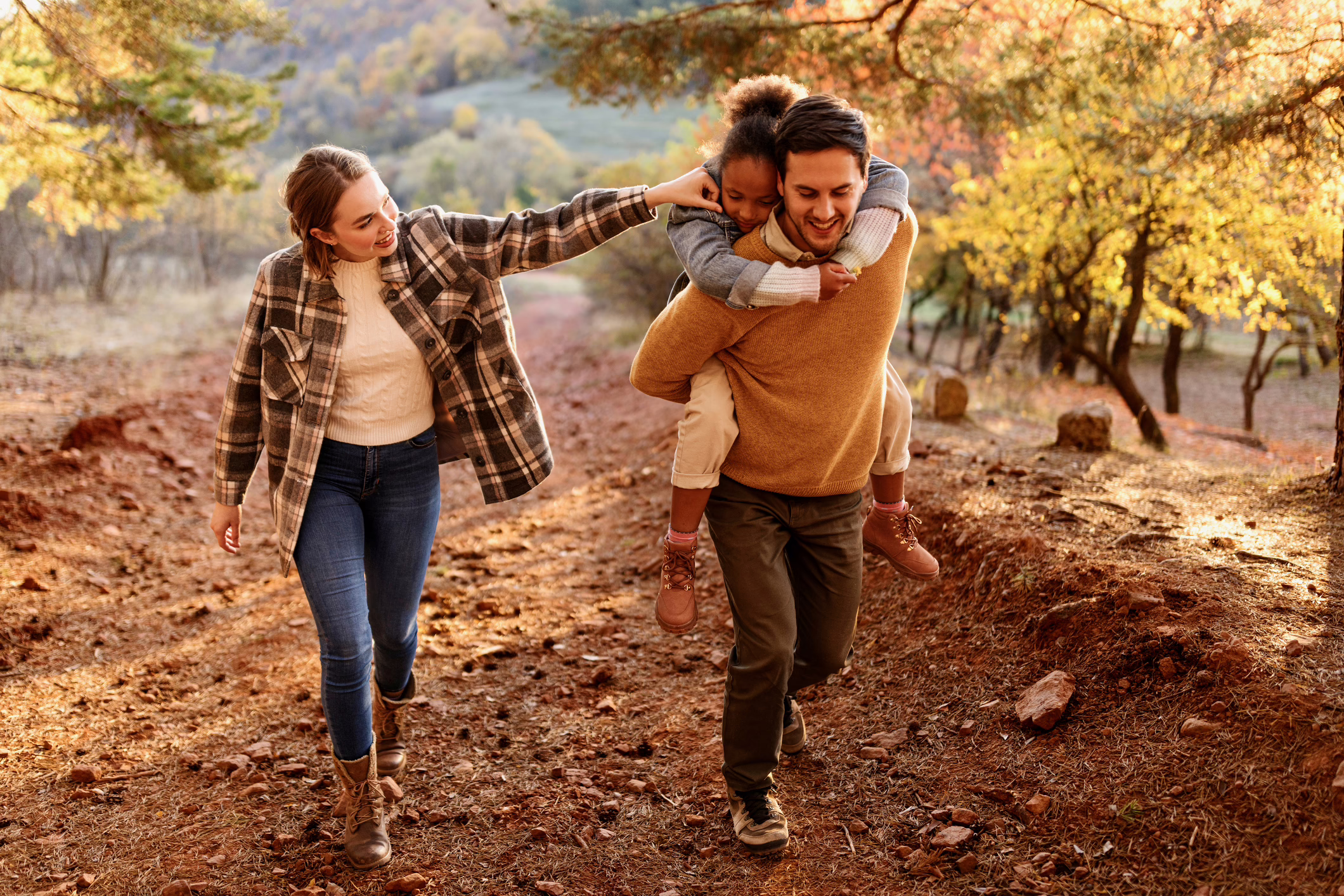 A couple and their daughter walking outdoors together in the fall
