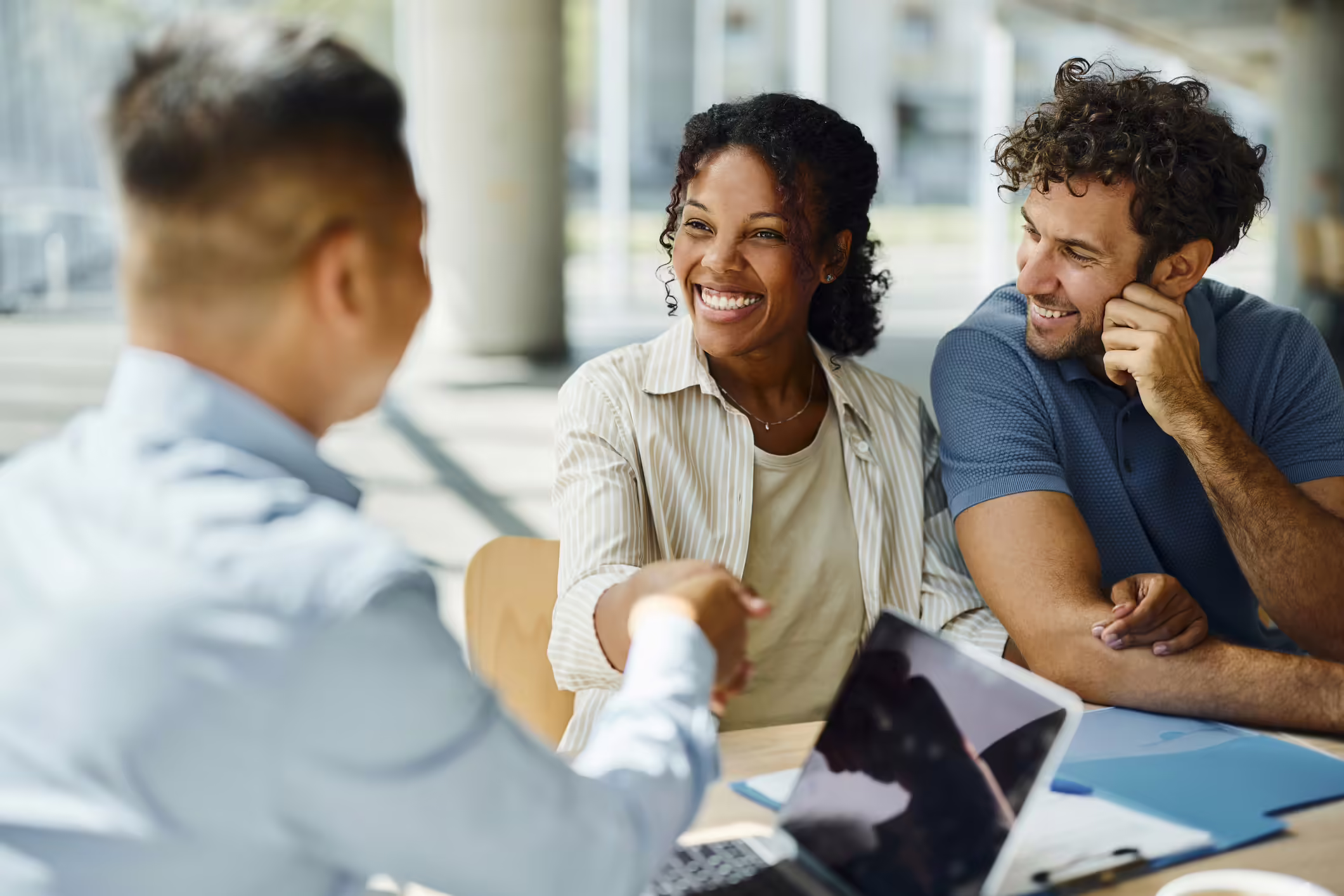 A couple meeting with their financial advisor. The woman is shaking hands with the advisor.