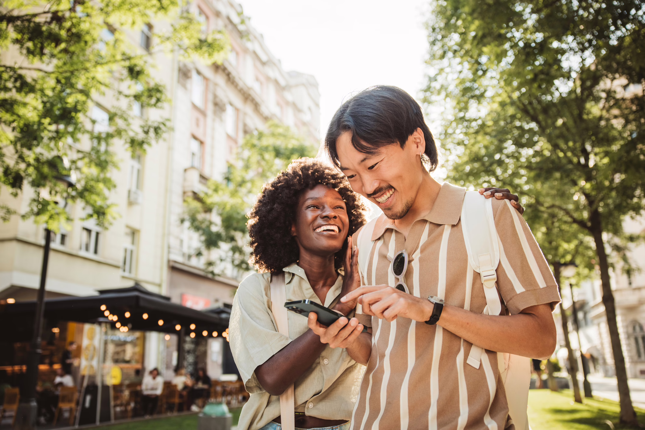 A young couple smiling and walking in an outdoor shopping area