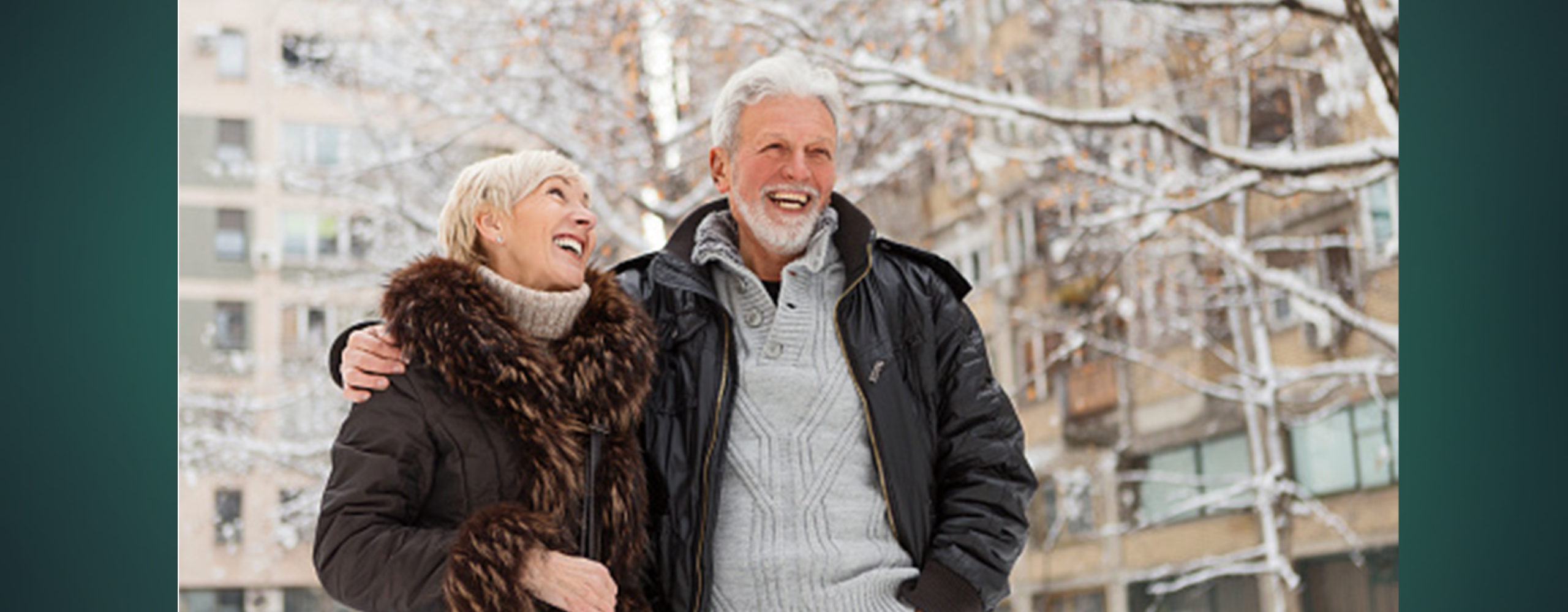 A smiling older couple walking outdoors together in the snow