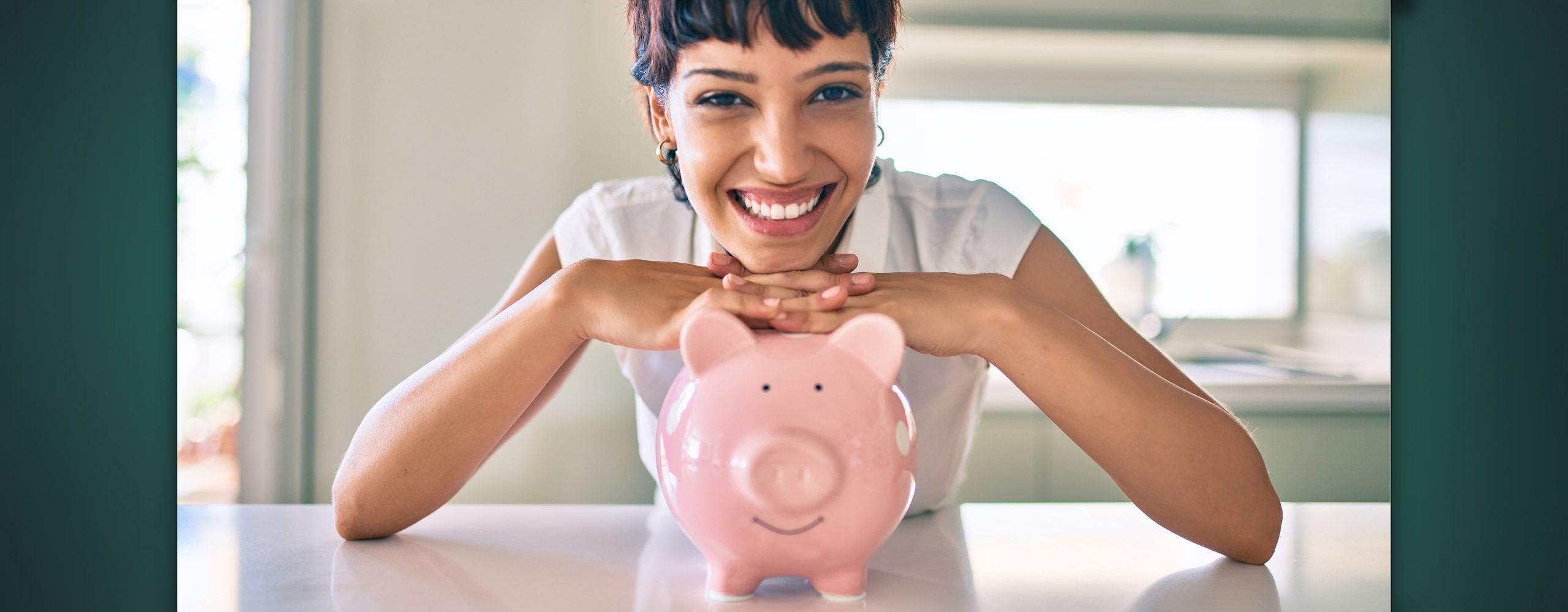 A smiling woman posing with a piggy bank