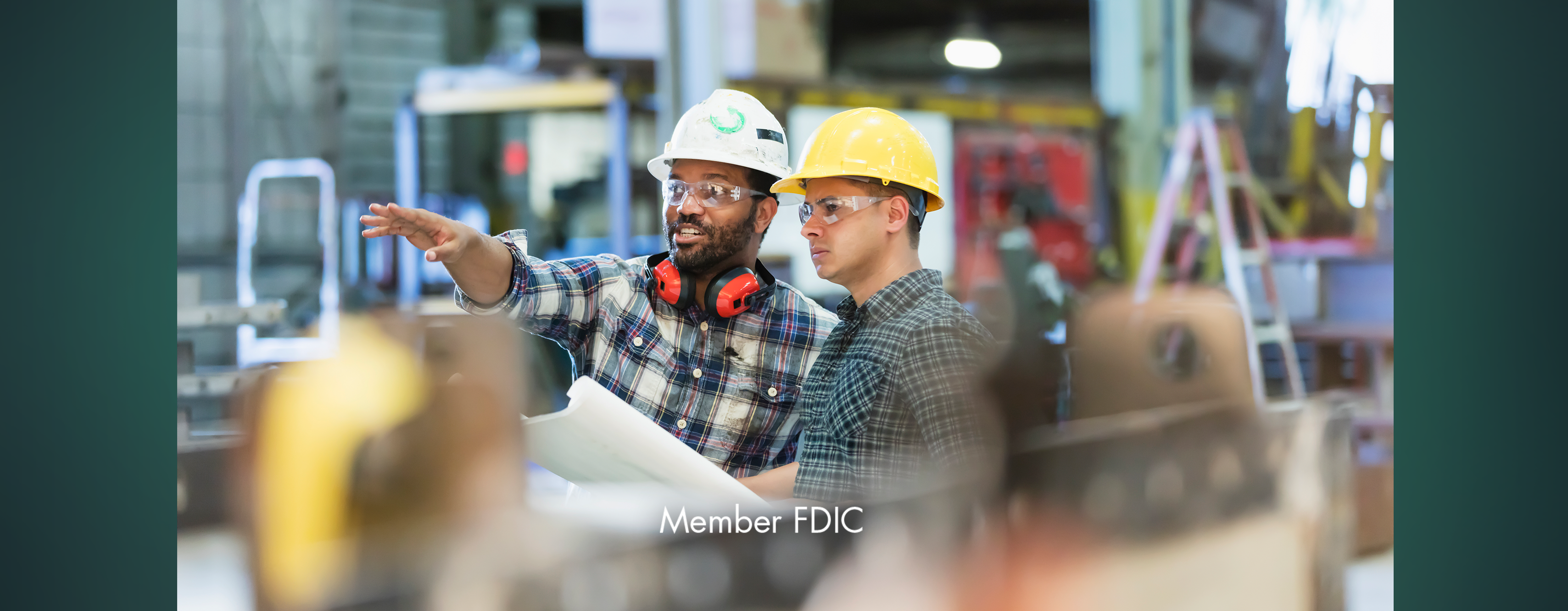 Two men in hard hats looking at construction plans together