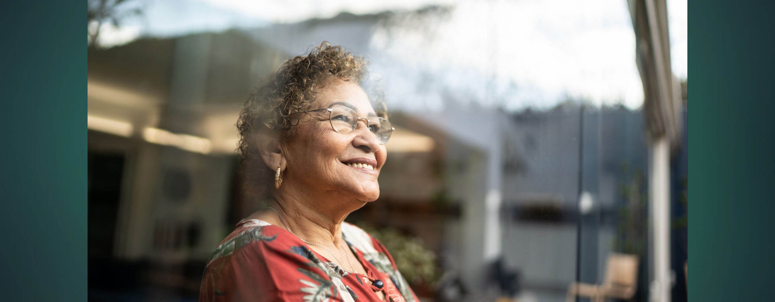 An older woman looking outside the window and smiling