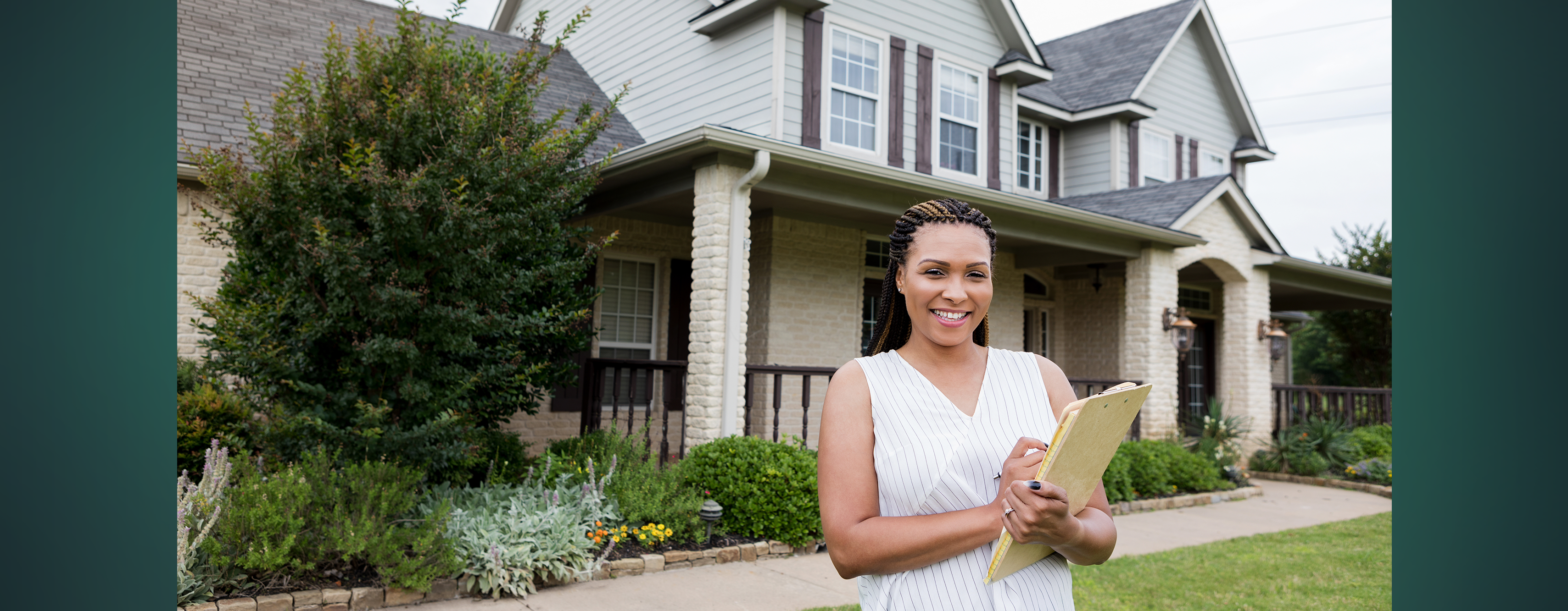A woman with a clipboard standing outside a white brick house