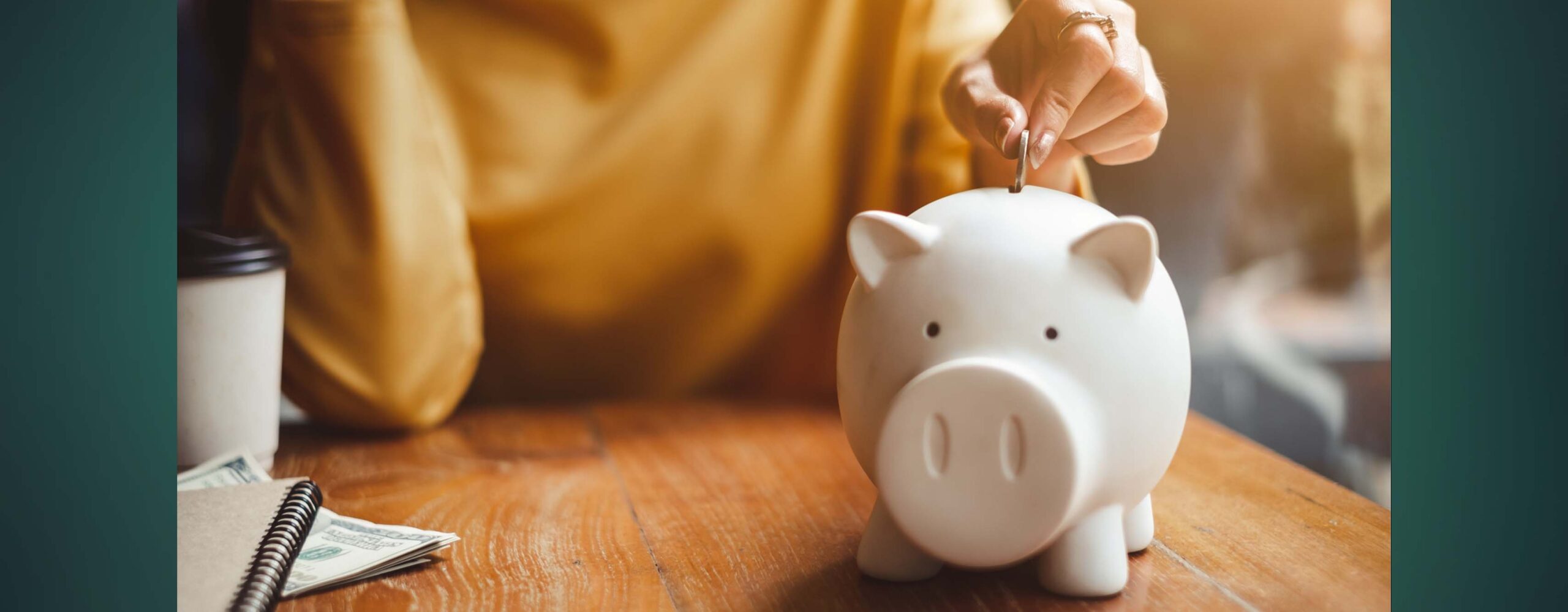 A person dropping a coin into a piggy bank