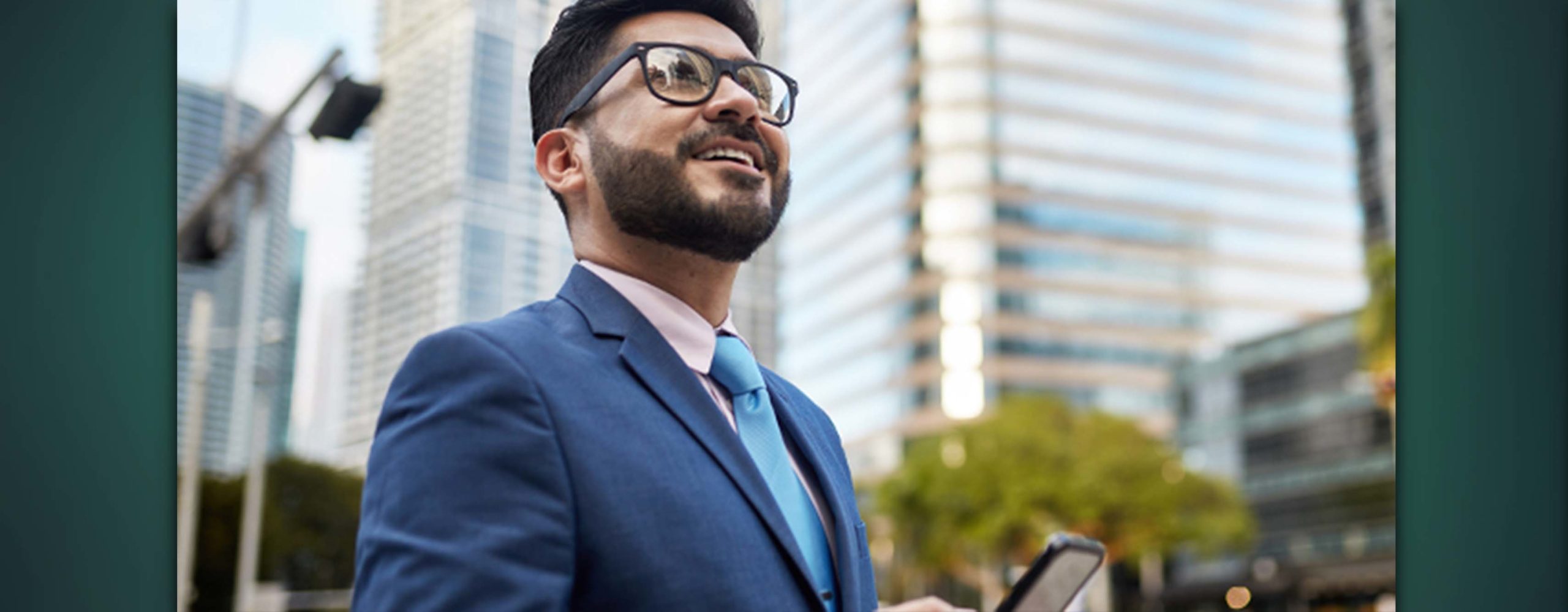 A man holding a cell phone outside a large business office